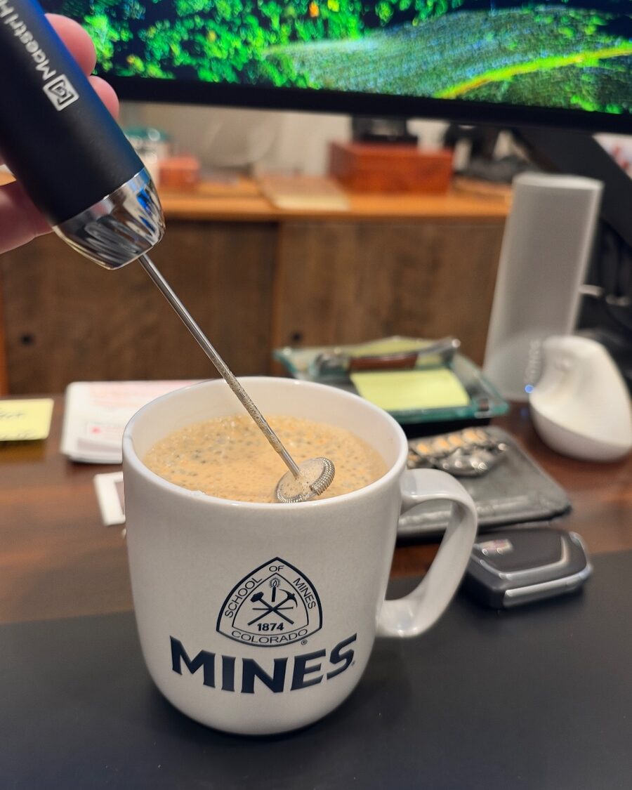 The LunaFro Max in hand, whisk down in a mug of coffee on his desk, a monitor behind